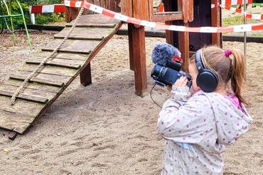 Auf dem Bild ist ein Kind mit einer Kamera zu sehen.