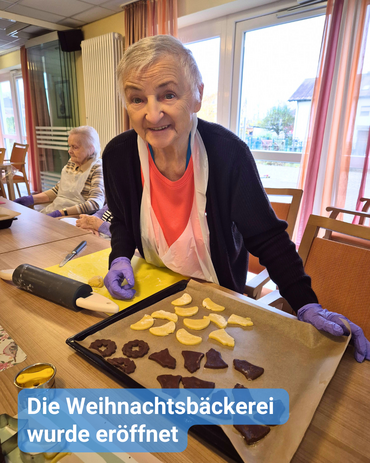 Seniorin sticht Plätzchen aus, Bildbeschriftung: “Die Weihnachtsbäckerei wurde eröffnet”