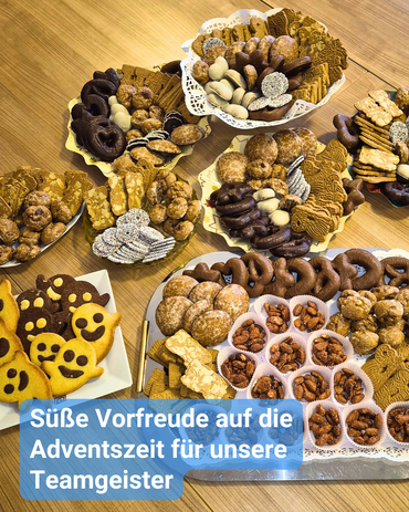 Ein Tisch voller Lebkuchen, Spekulatius, Pfeffernüsse, gebrannter Mandeln und ganz besonderer Teamgeist-Kekse. Bildbeschriftung: „Süße Vorfreude auf die Adventszeit für unsere Teamgeister“