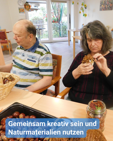 Eine Frau und ein Mann basteln gemeinsam am Tisch. Herbsteko. Bildbeschriftung: Gemeinsam kreativ sein und Naturmaterialien nutzen