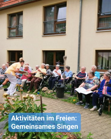 Eine Gruppe Senioren sitzt im Kreis im Hof/Garten eines Pflegeheims. Bildbeschriftung: Aktivitäten im Freien: Gemeinsames Singen