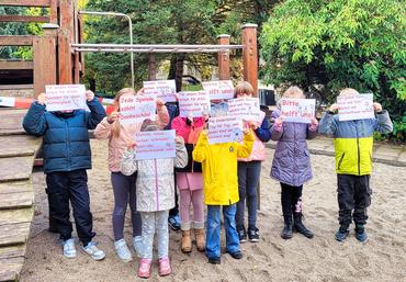 Auf dem Bild sind einige Kinder mit Schildern zu sehen.