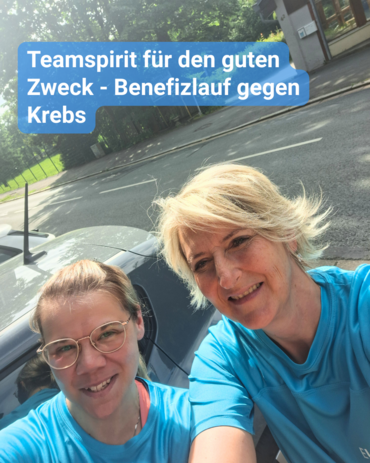 Zwei Frauen posieren eng beieinander für ein Selfie. Beide tragen leuchtend blaue T-Shirts. Die Frau links trägt Brille und hat ihr Haar zurückgebunden. Die Frau rechts hat blondes, kurz gestyltes, gestuftes Haar. Beide lächeln herzlich.  Hinter ihnen sieht man ein graues Auto und eine Straße, die von Bäumen gesäumt ist, im Hintergrund.  In einer blauen Sprechblase am oberen Rand des Bildes steht: „Teamspirit für den guten Zweck – Benefizlauf gegen Krebs“.