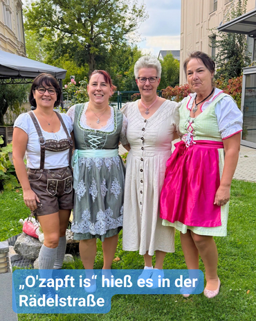 Vier Damen stehen in einem Innenhof. Sie tragen bayerische Trachtenmode, von Lederhose bis zum Dirndl. Bildbeschriftung: „O'zapft is" hieß es in der Rädelstraße