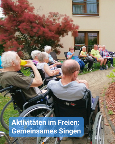 Eine Gruppe Senioren sitzt im Kreis im Hof/Garten eines Pflegeheims. Bildbeschriftung: Aktivitäten im Freien: Gemeinsames Singen